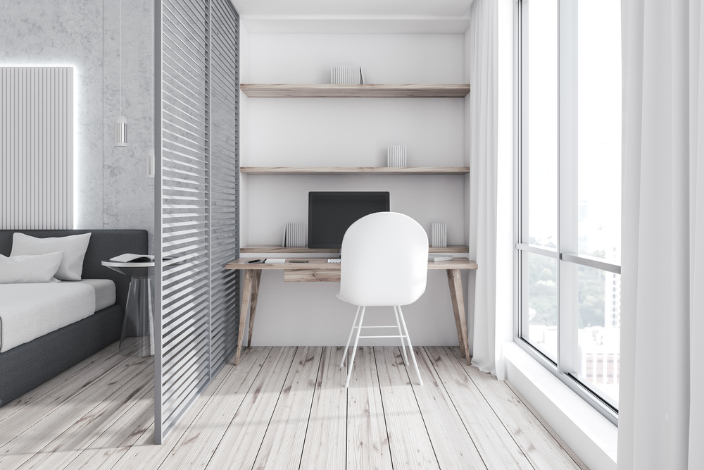 Habitación luminosa y funcional con un diseño minimalista que integra una zona de trabajo compacta y estéticamente armoniosa junto a la cama.